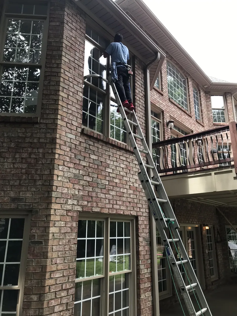 Cleaning second-story windows of a brick home in Charlotte