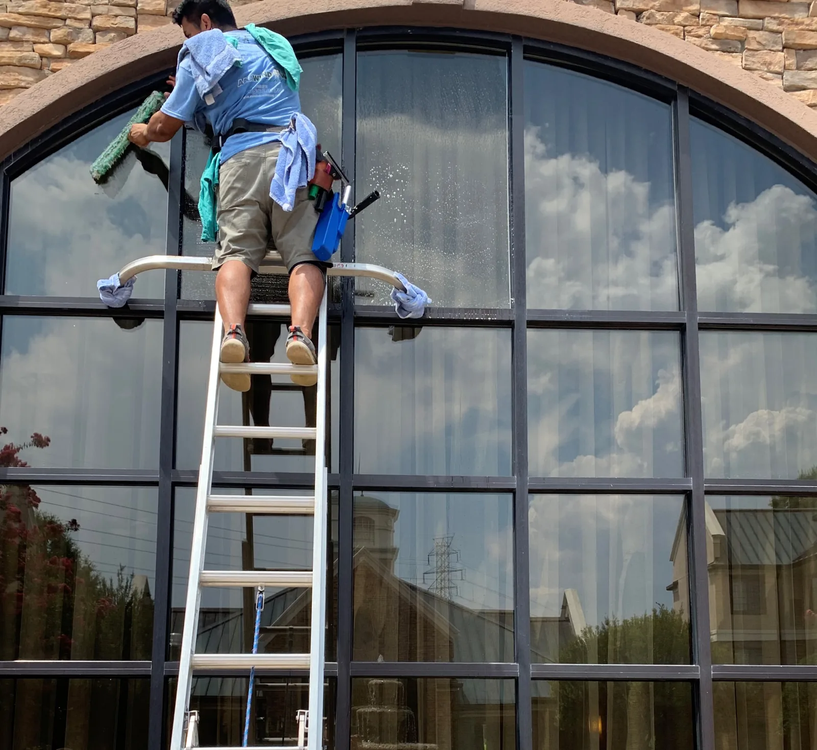 AAA technician cleaning a large arched window in Charlotte