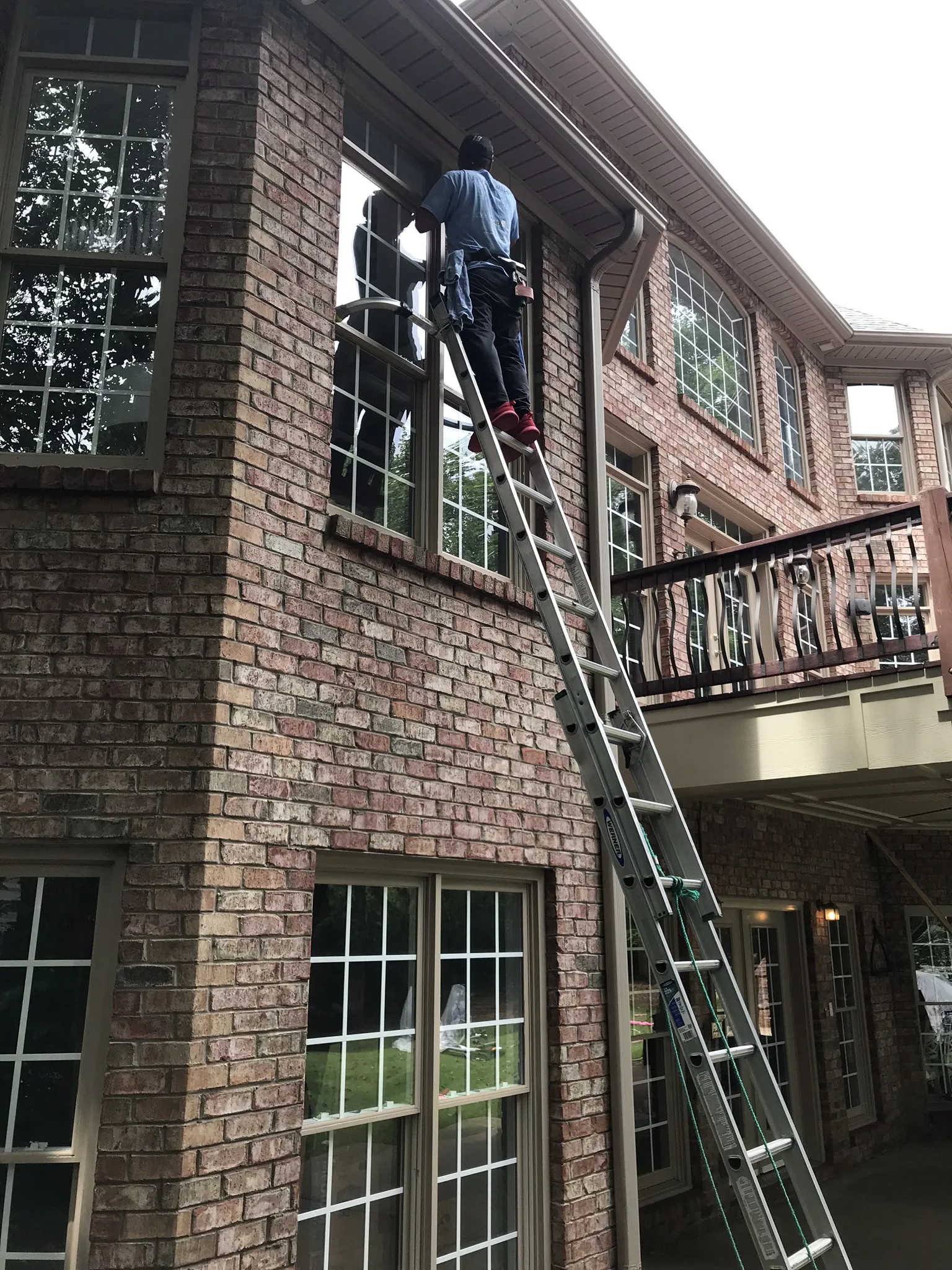 Cleaning second-story windows of a brick home in Charlotte