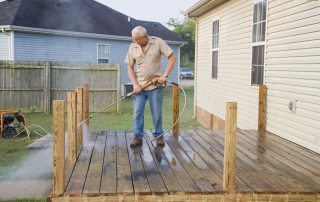 Man pressure washing his deck