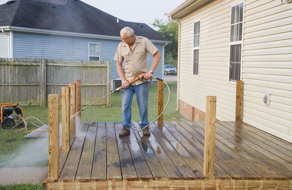 Man pressure washing his deck