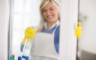 Woman wearing apron sprays window cleaning product on glass