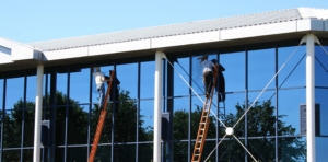 Two window tinters are working on an office building